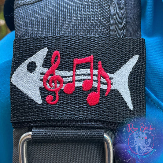 Embroidered BCD Tag Featuring a silver fish skeleton grooving with music notes along its spine on Black Webbing. Made for scuba divers by Rinn Stitches in Maui, Hawaii