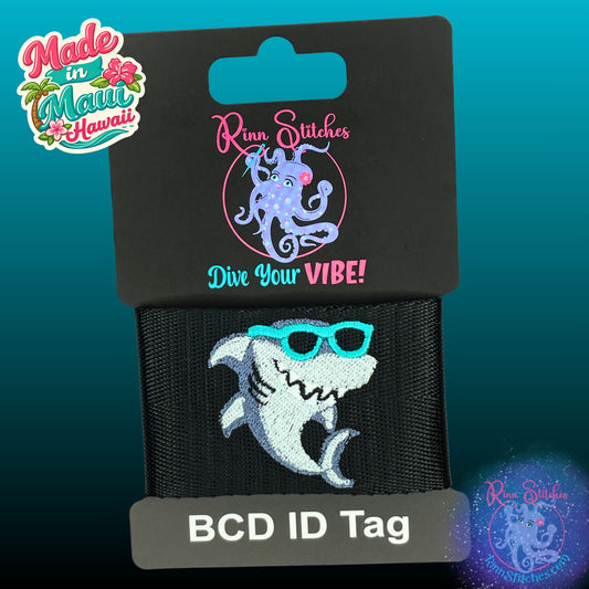 Embroidered BCD Tag with a cute cartoon style shark wearing teal sunglasses on Black Webbing. Made for scuba divers by Rinn Stitches in Maui, Hawaii
