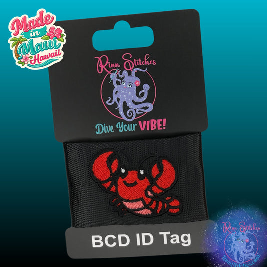 Embroidered BCD Tag on black webbing featuring a red and coral cute crawdad design. Made by Rinn Stitches in Maui, Hawaii