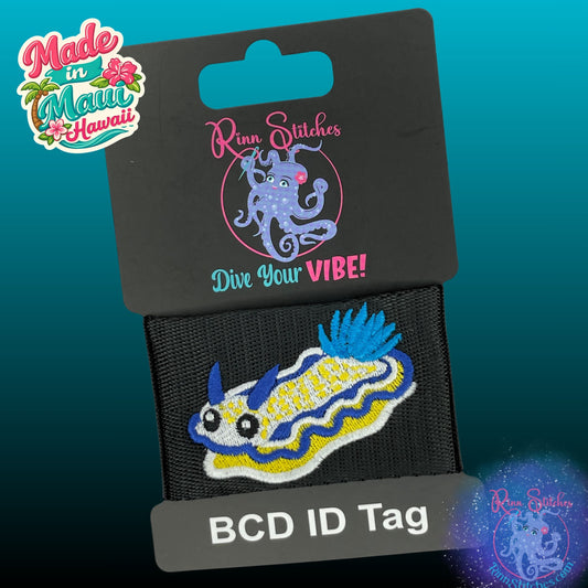 Cute Imperial Nudibranch embroidered in a cartoon style with big eyes onto black webbing. BCD Tag made for outdoor adventures. Made by Rinn Stitches on Maui, Hawaii