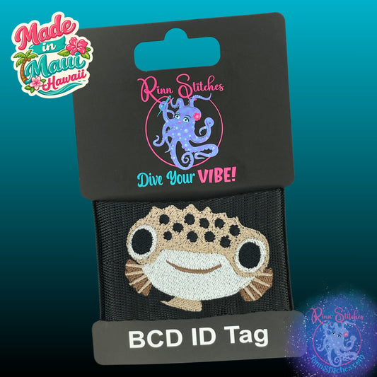 Embroidered BCD Tag Featuring a smiling pufferfish design that’s equal parts cute and eye-catching on Black Webbing. Made for scuba divers by Rinn Stitches in Maui, Hawaii