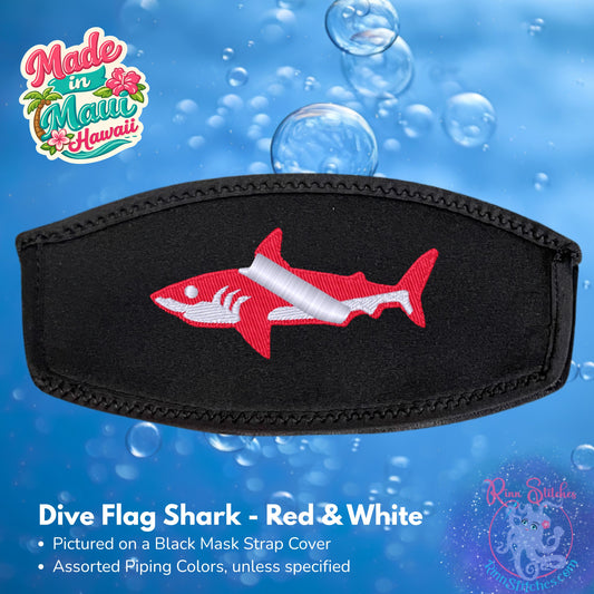 A black neoprene mask strap cover featuring an embroidered red and white dive flag shark design, shown against a blue water-themed background with bubbles. Made by Rinn Stitches in Maui, Hawaii