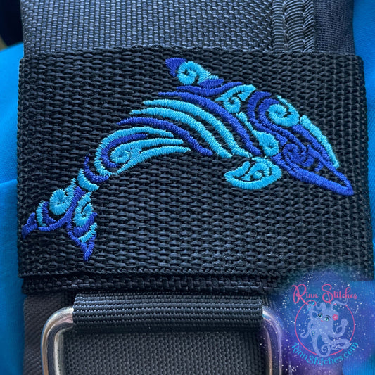 Embroidered BCD Tag Featuring a two-tone tribal dolphin design shown in Blue Abyss and Blue Skies Thread on Black Webbing. Made for scuba divers by Rinn Stitches in Maui, Hawaii