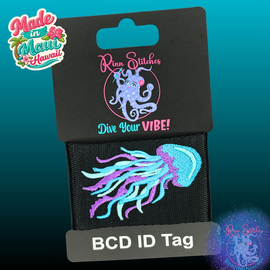 Embroidered BCD Tag Featuring an elegant jellyfish design capturing the fluid motion of a blue and purple jellyfish drifting through the reef on Black Webbing. Made for scuba divers by Rinn Stitches in Maui, Hawaii