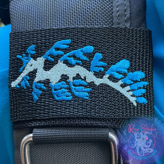 Embroidered BCD Tag Featuring a flowing leafy sea dragon design shown in Sea Foam and Ocean on Black Webbing. Made for scuba divers by Rinn Stitches in Maui, Hawaii
