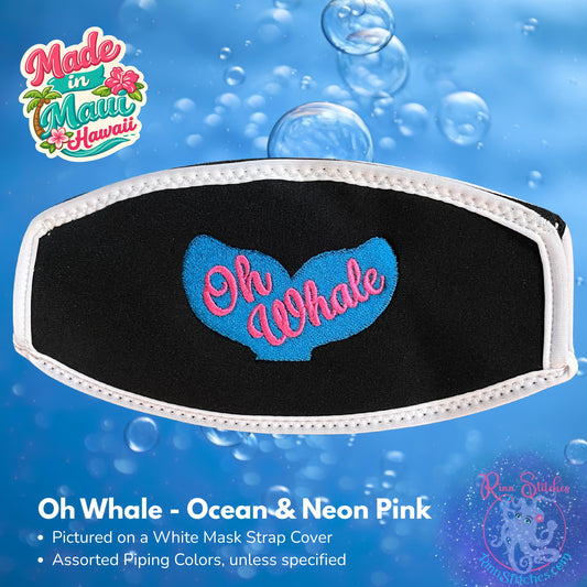 A black neoprene mask strap cover with a white piping featuring a whale tail design and the text "Oh Whale" across the tail. Made in Maui, Hawaii by Rinn Stitches.