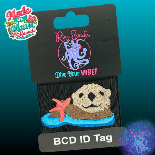 Embroidered BCD Tag with Featuring an adorable sea otter holding a sea star, with a coral colored sea star on Black Webbing. Made for scuba divers by Rinn Stitches in Maui, Hawaii
