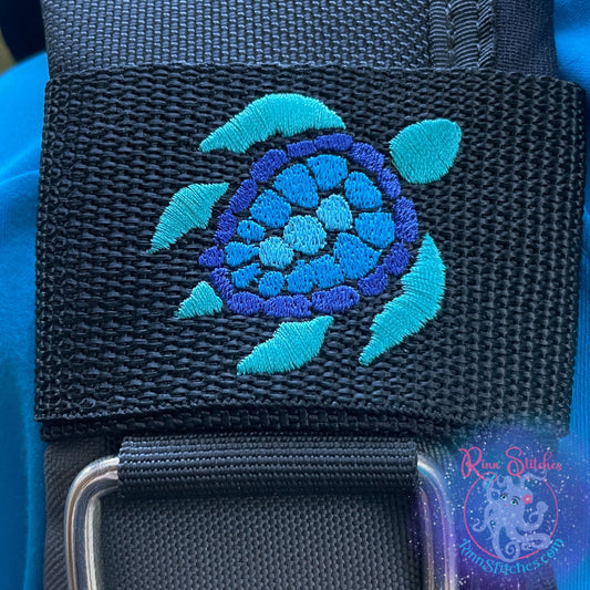 Embroidered BCD Tag Featuring a stylized sea turtle design with a multi-colored shell in Teals and Blues for added visual interest on Black Webbing. Made for scuba divers by Rinn Stitches in Maui, Hawaii