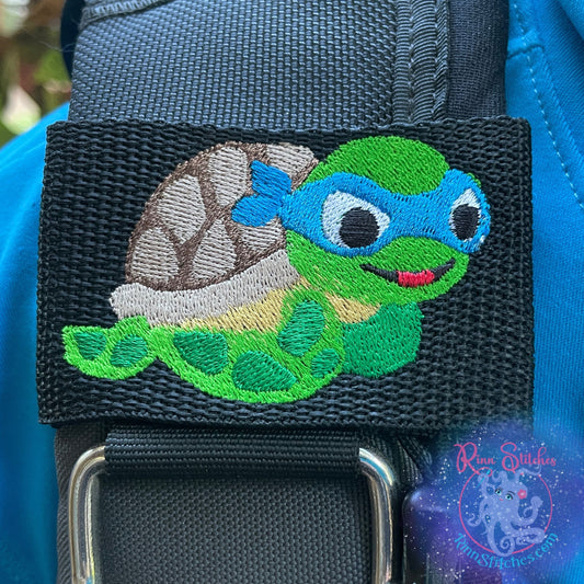 Embroidered BCD Tag Featuring a sea turtle ninja design with ocean color mask on Black Webbing. Made for scuba divers by Rinn Stitches in Maui, Hawaii