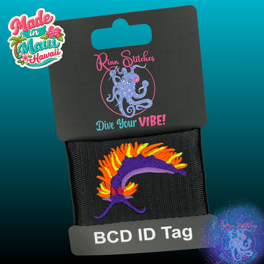 Embroidered BCD Tag featuring a purple, neon orange and neon yellow Spanish Shawl Nudibranch on black webbing. Made for adventure gear by Rinn Stitches in Maui, Hawaii