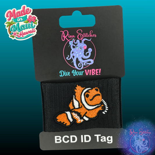 An embroidered BCD ID tag featuring an orange and white clownfish, attached to a black card backing with 'Rinn Stitches Dive Your VIBE!' branding. The image includes a 'Made in Maui Hawaii' badge